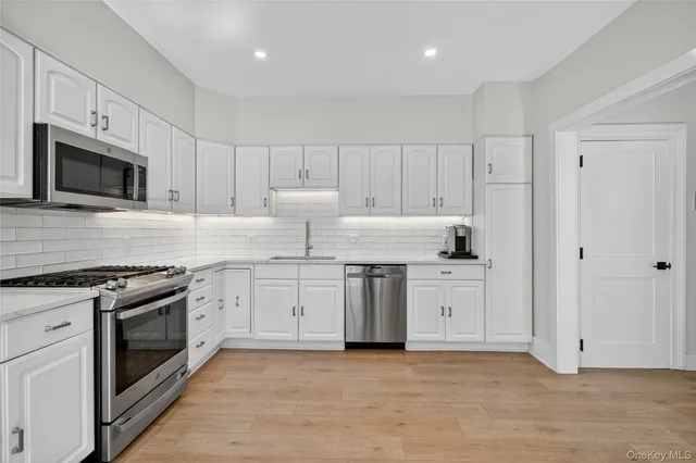 a kitchen with granite countertop white cabinets stainless steel appliances and a sink