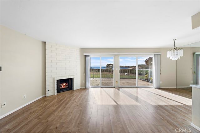 an empty room with wooden floor fireplace and windows