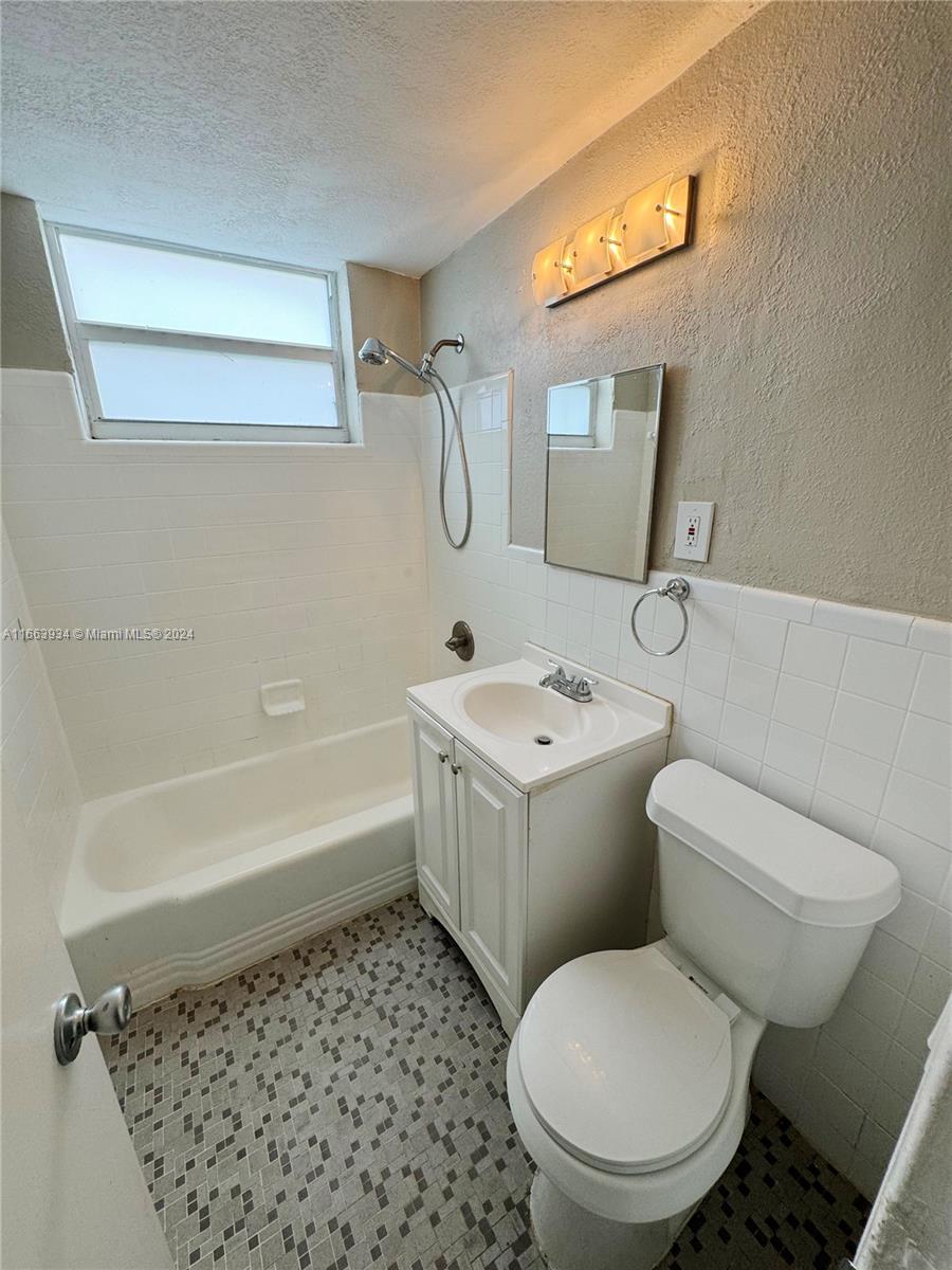 620 76th Street, Unit 7 Miami Beach, FL 33141 - Photo 15 of 17 a white toilet sitting next to a bathroom sink and tub