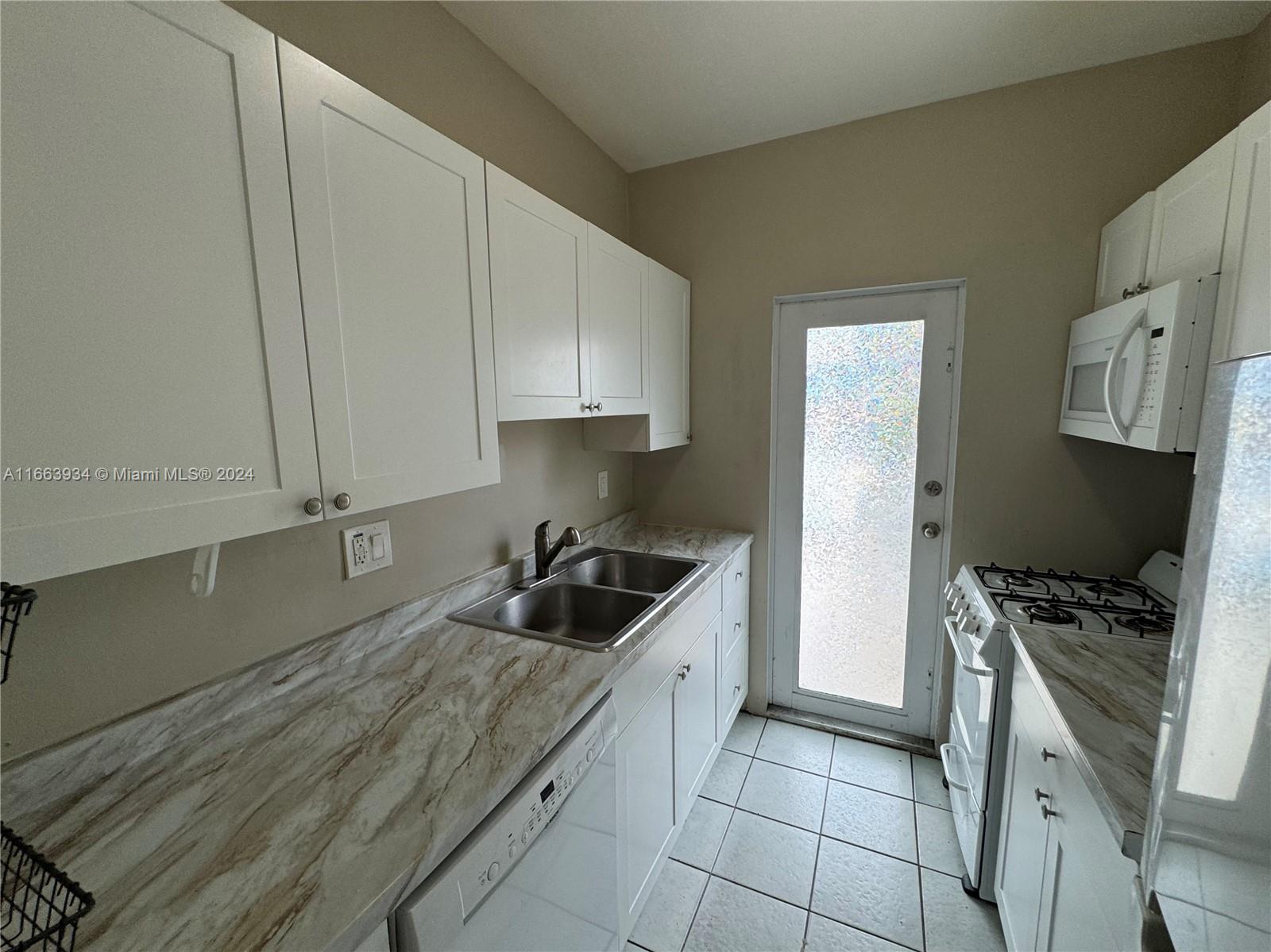 620 76th Street, Unit 7 Miami Beach, FL 33141 - Photo 5 of 17 a kitchen with a sink a stove and cabinets