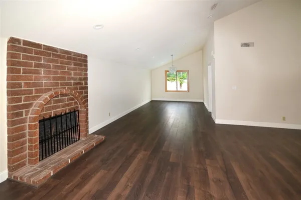 an empty room with wooden floor and fireplace