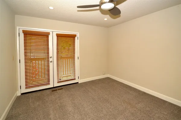 an empty room with a ceiling fan and carpet