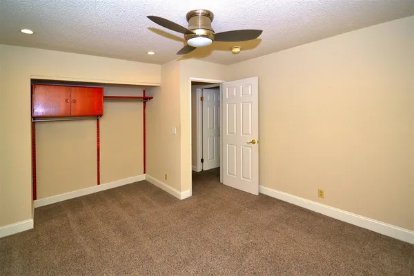an empty room with closet and a chandelier fan