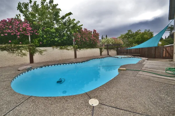 a view of a swimming pool with a patio and wooden fence