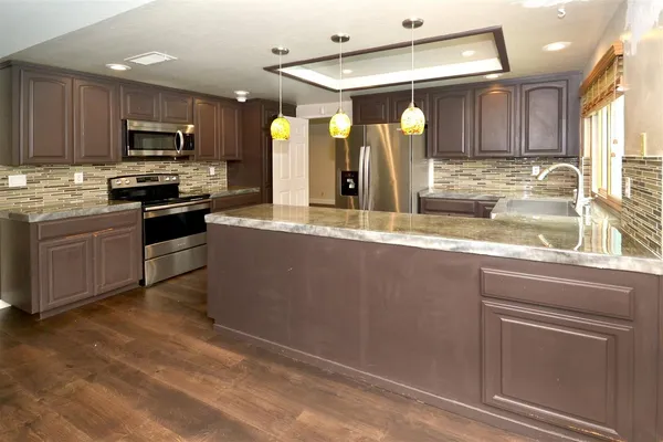 a kitchen with stainless steel appliances granite countertop a sink a stove and cabinets