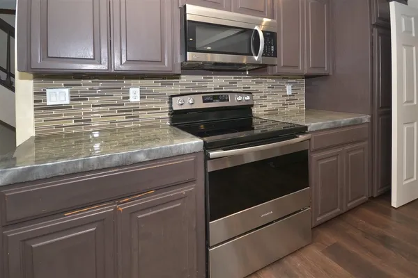 a kitchen with granite countertop a stove microwave and sink