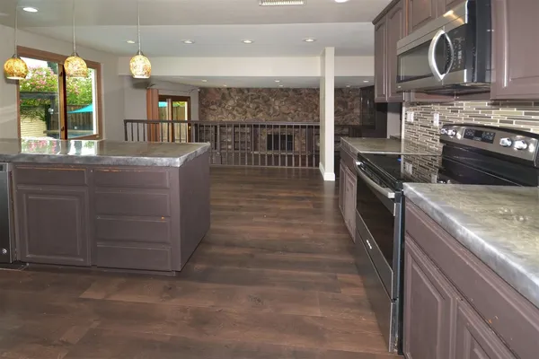 a kitchen with kitchen island granite countertop a stove and a sink