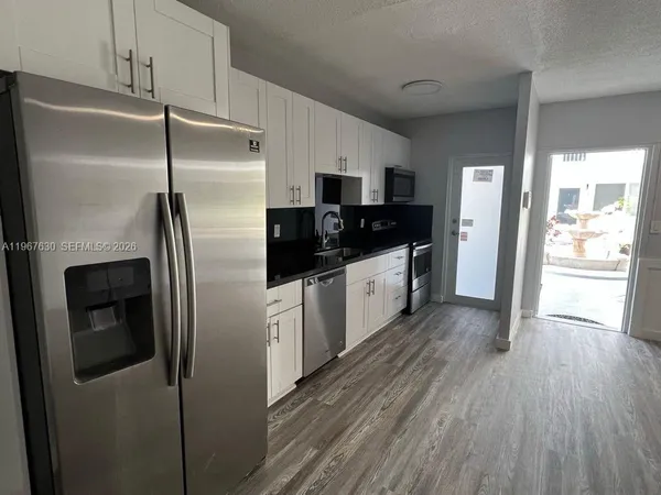 a kitchen with stainless steel appliances a refrigerator a sink and wooden floors