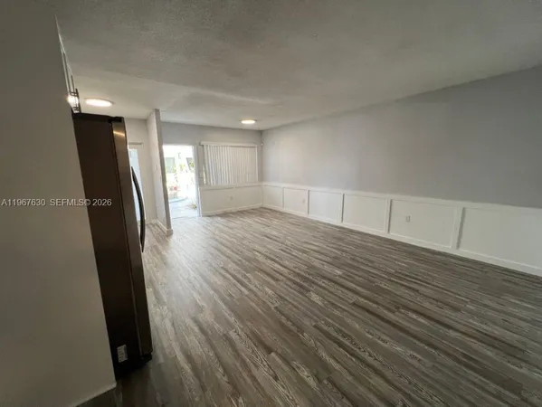 an empty room with wooden floor and glass door