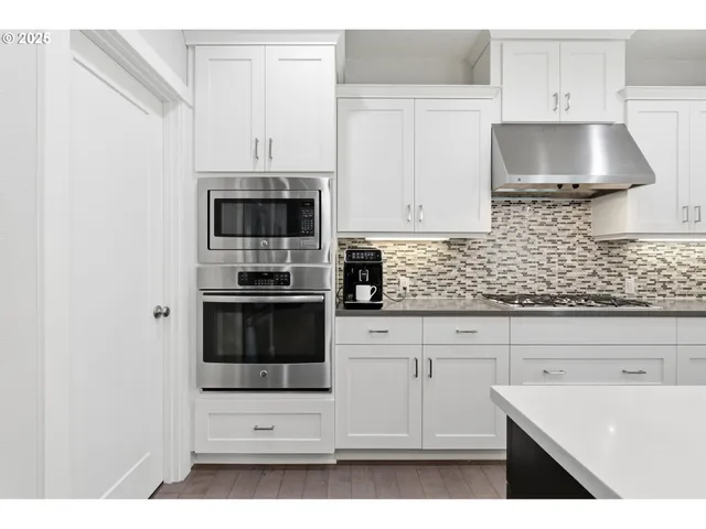 a kitchen with granite countertop white cabinets and stainless steel appliances