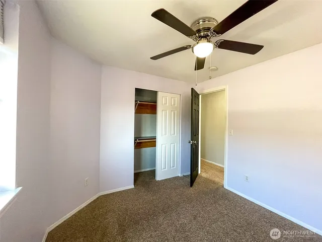 an empty room with windows and fan