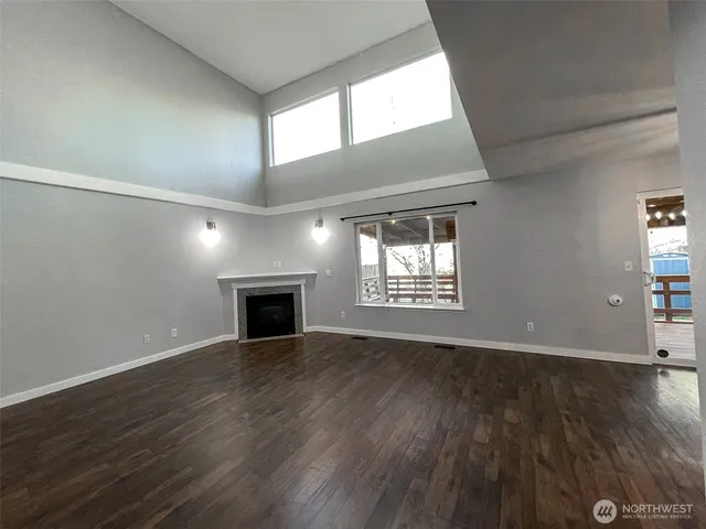 an empty room with wooden floor fireplace and windows