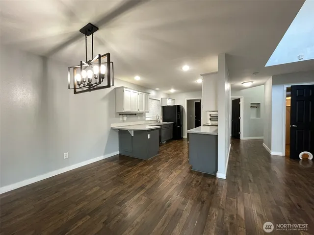 a large kitchen with stainless steel appliances kitchen island a large counter top and wooden floors