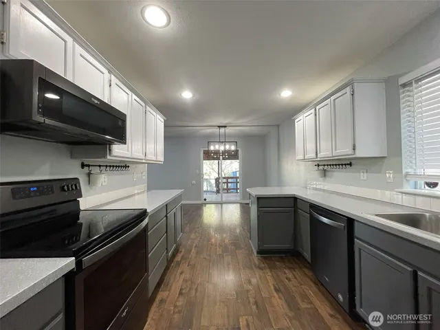 a kitchen with a sink wooden floor and stainless steel appliances
