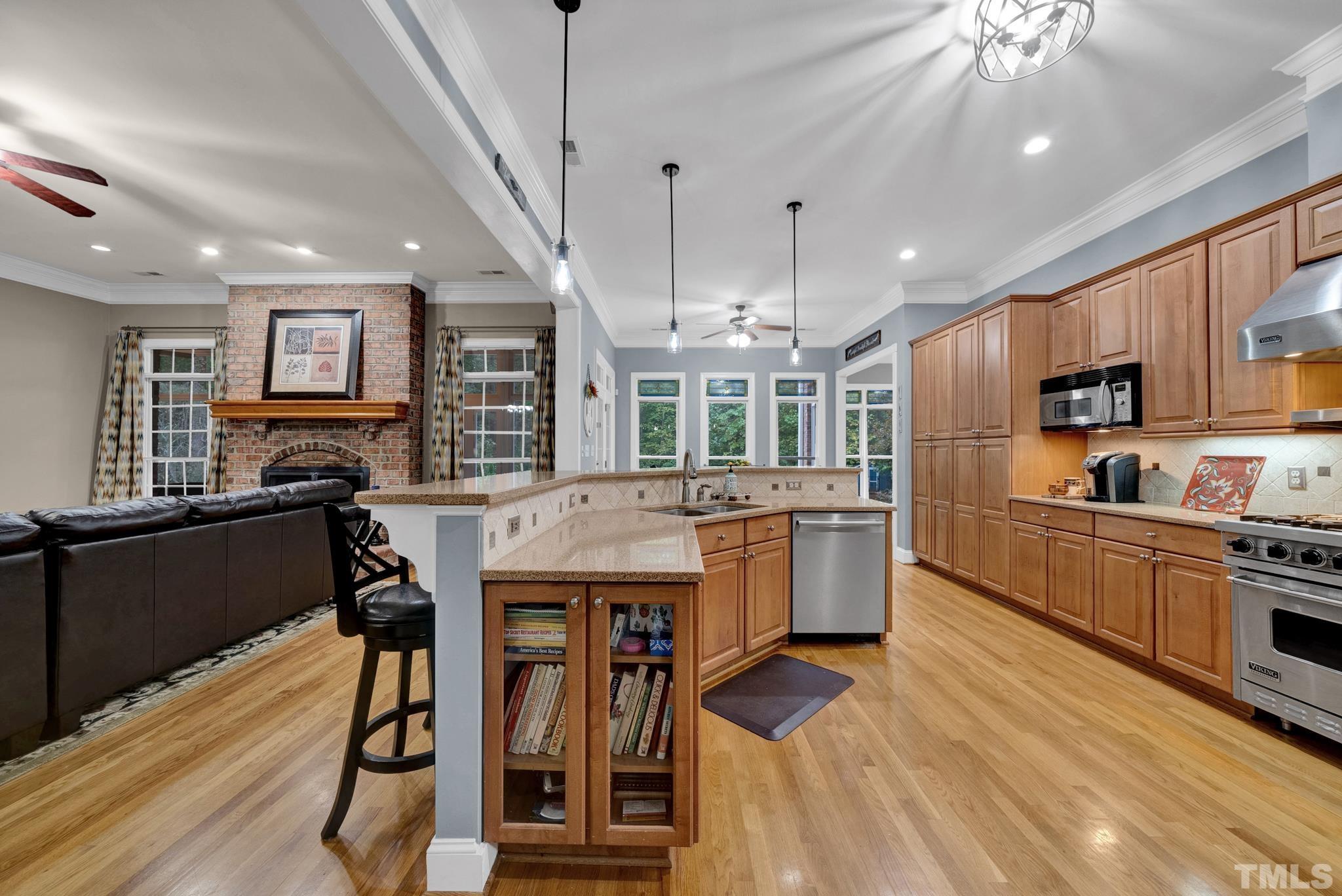 3249 Grand Oak Lane New Hill, NC 27562 - Photo 17 of 65 a kitchen with stainless steel appliances kitchen island granite countertop a refrigerator a stove a sink dishwasher a dining table and chairs with wooden floor