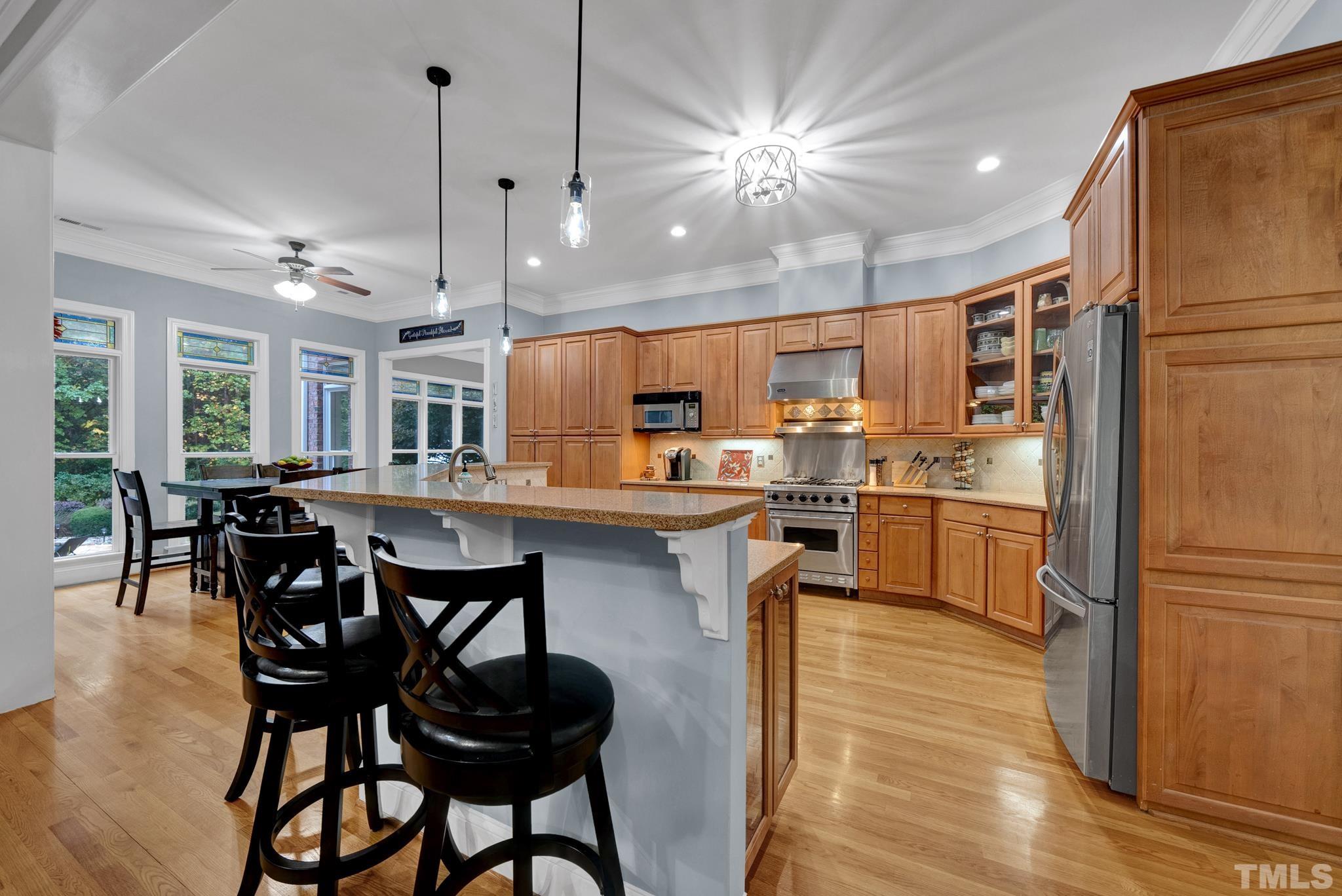 3249 Grand Oak Lane New Hill, NC 27562 - Photo 18 of 65 a kitchen with stainless steel appliances a table chairs refrigerator and microwave