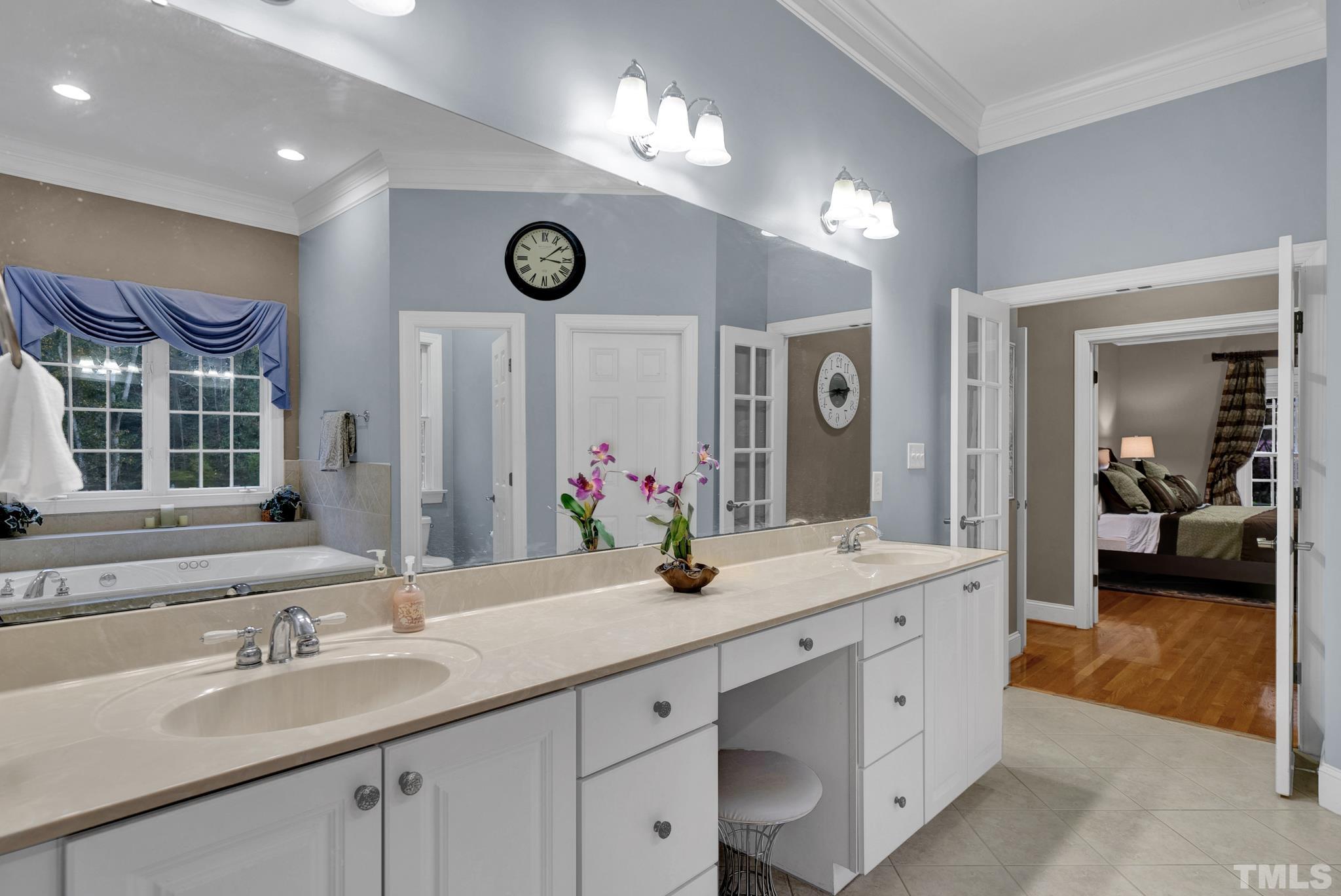 3249 Grand Oak Lane New Hill, NC 27562 - Photo 25 of 65 a bathroom with double vanity sinks a vanity a mirror and a bathtub