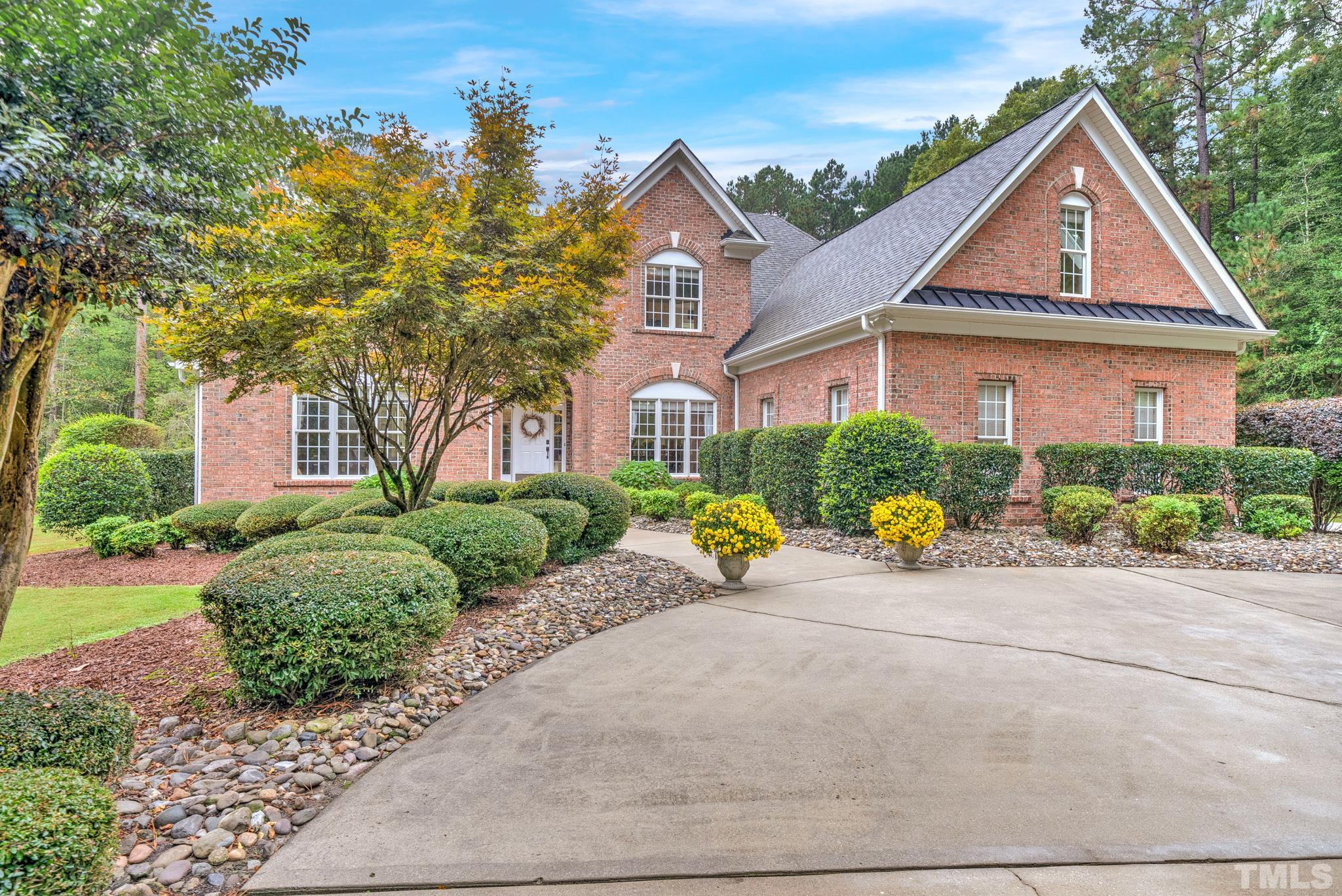 3249 Grand Oak Lane New Hill, NC 27562 - Photo 50 of 65 a view of a brick house with a yard plants and palm trees