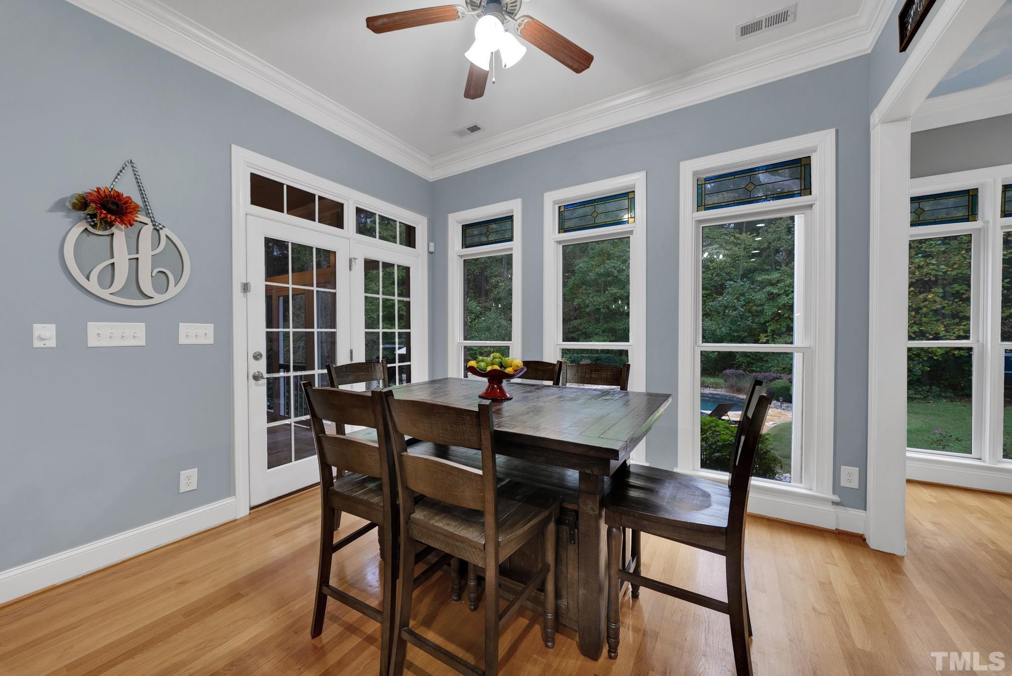 3249 Grand Oak Lane New Hill, NC 27562 - Photo 58 of 65 a dining room with wooden floor a chandelier a wooden table and chairs
