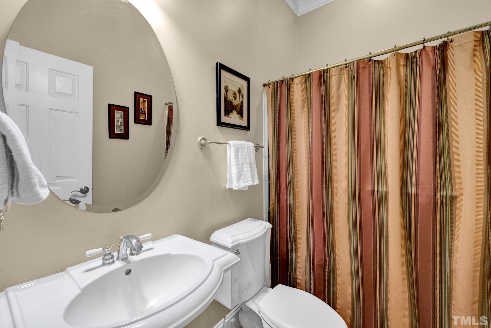 3249 Grand Oak Lane New Hill, NC 27562 - Photo 62 of 65 a bathroom with a sink a mirror a toilet and a window