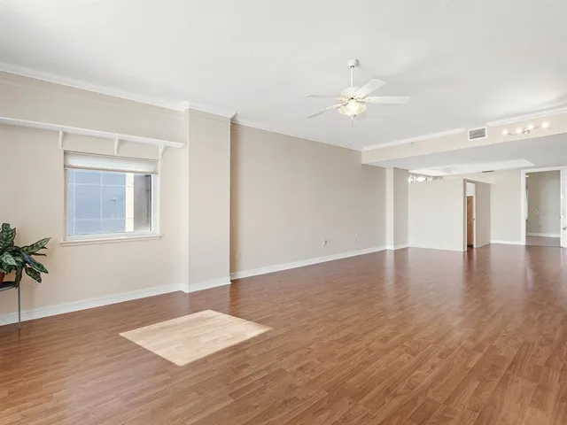 a view of an empty room with window and wooden floor