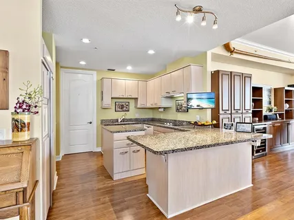 a kitchen with stainless steel appliances granite countertop a stove top oven a refrigerator a sink and dishwasher with wooden floor