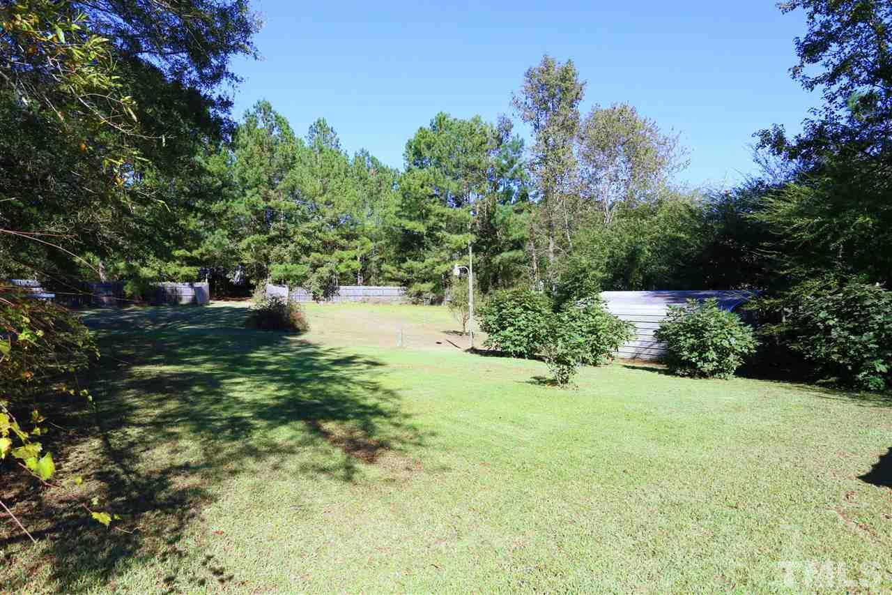 323 Aquilla Road, Unit A Benson, NC 27504 - Photo 4 of 25 a view of a garden with plants and a large tree