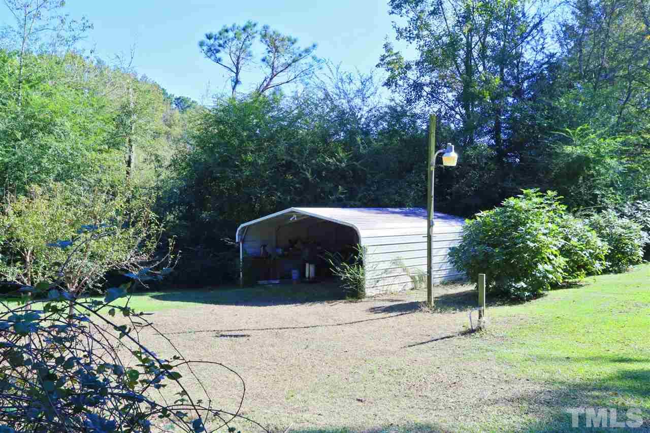 323 Aquilla Road, Unit A Benson, NC 27504 - Photo 7 of 25 a backyard of a house with large trees and plants
