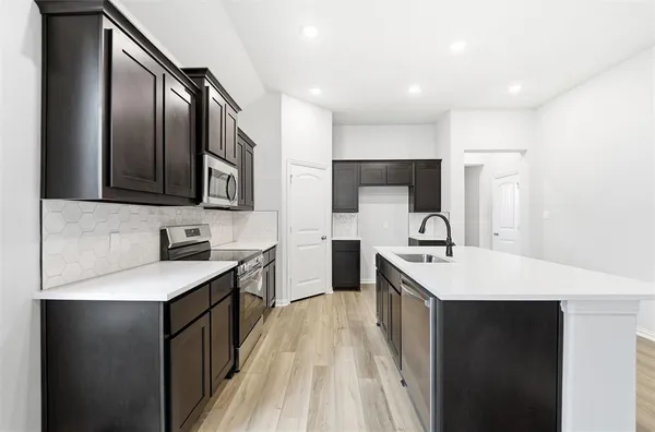 a kitchen with stainless steel appliances granite countertop a sink stove refrigerator and cabinets