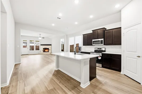 a kitchen with stainless steel appliances a sink dishwasher a refrigerator and a stove top oven with wooden floor