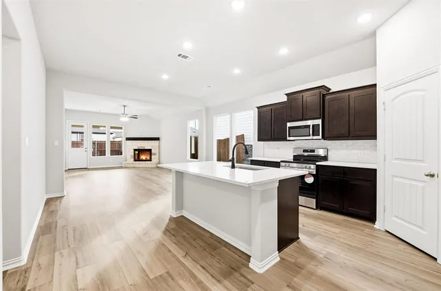 a kitchen with stainless steel appliances a sink dishwasher a refrigerator and a stove top oven with wooden floor