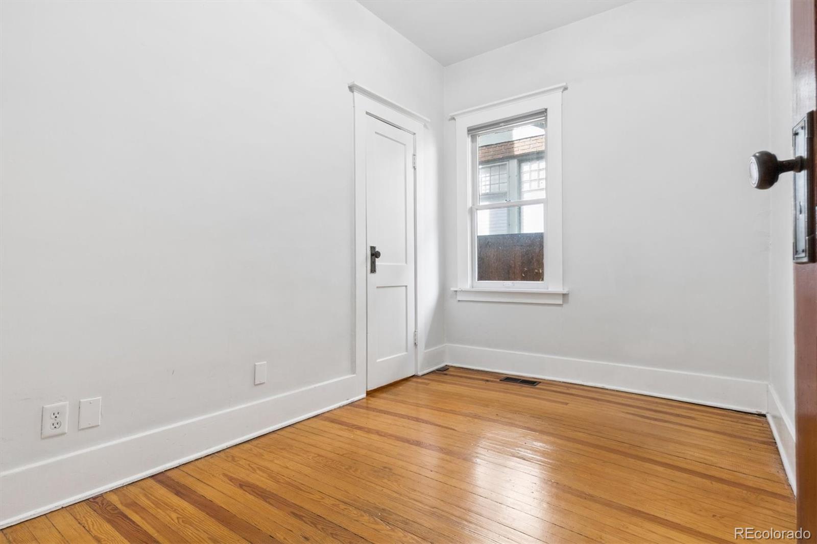 736 York Street Denver, CO 80206 - Photo 22 of 50 an empty room with wooden floor and windows