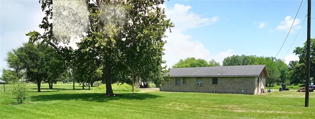 a view of a big yard with a fountain and large trees