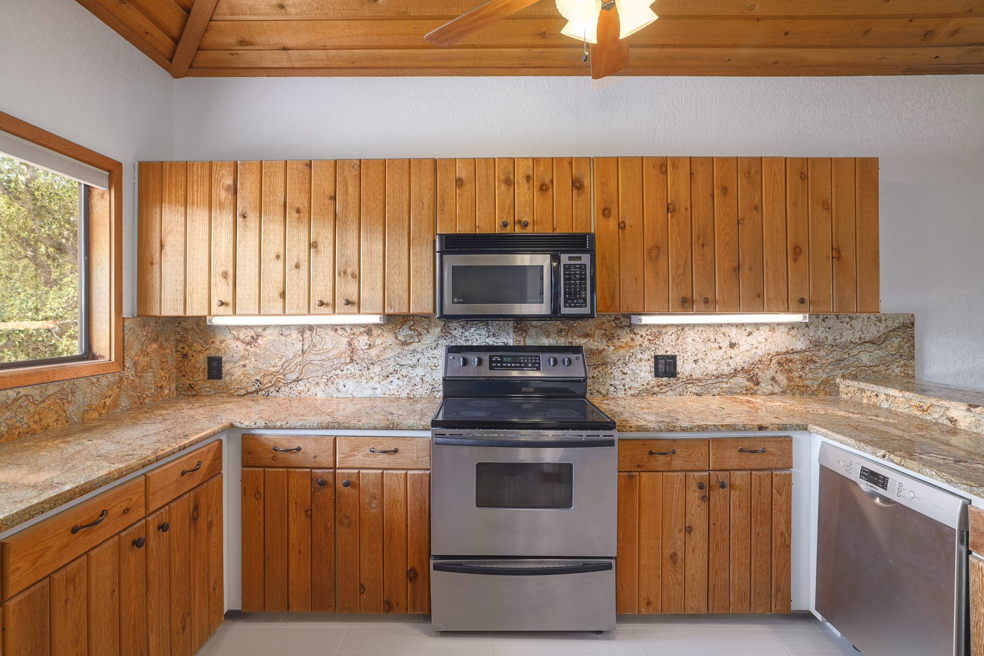 313 Kendall Road Spicewood, TX 78669 - Photo 10 of 34 Kitchen with stainless steel appliances, tasteful backsplash, light stone countertops, wooden ceiling, and brown cabinets