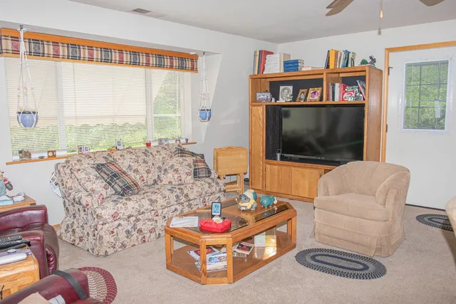 a living room with furniture a flat screen tv and a floor to ceiling window