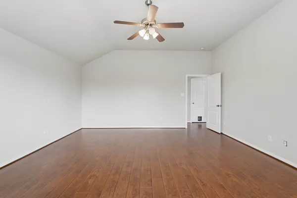 a view of an empty room with chandelier fan and wooden floor