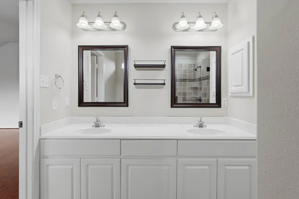 a bathroom with double vanity sinks and a mirror