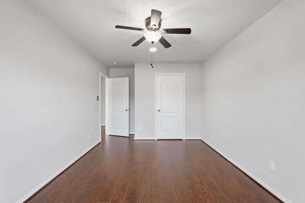 an empty room with wooden floor and ceiling fan