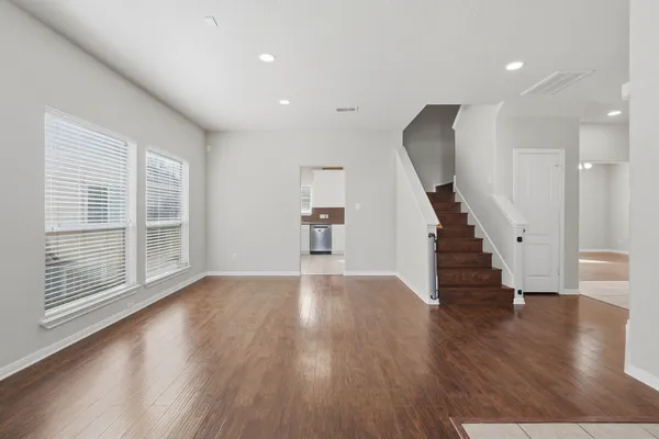 a view of empty room with wooden floor and stairs