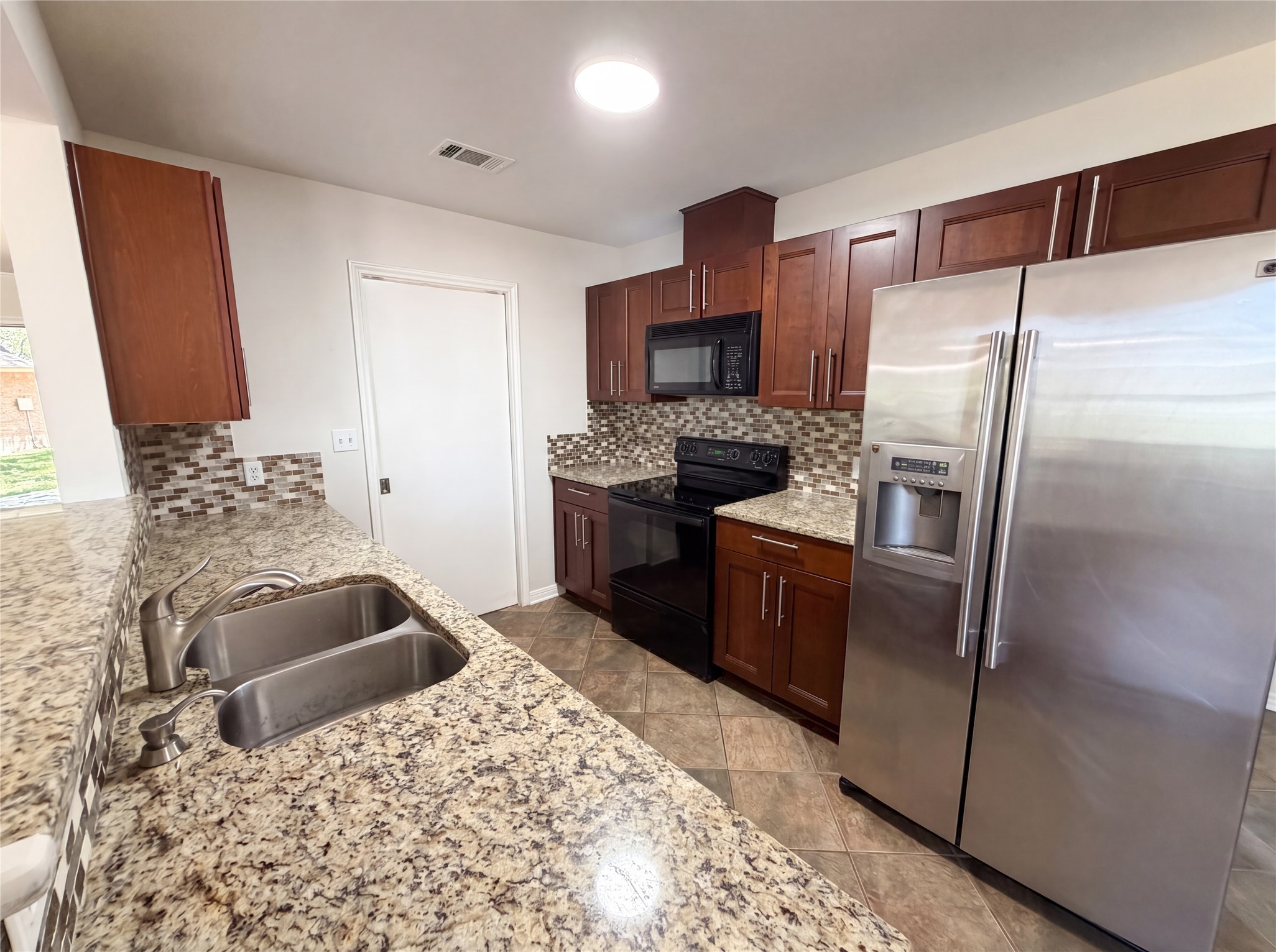 1111 North Riviera Circle Cedar Park, TX 78613 - Photo 6 of 17 Kitchen featuring granite-style countertops, mosaic tile backsplash, dark wood cabinetry, a stainless steel refrigerator, and a black electric range with an overhead microwave