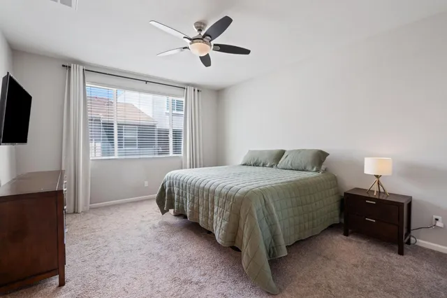 a spacious bedroom with a bed and a flat tv screen on a dresser