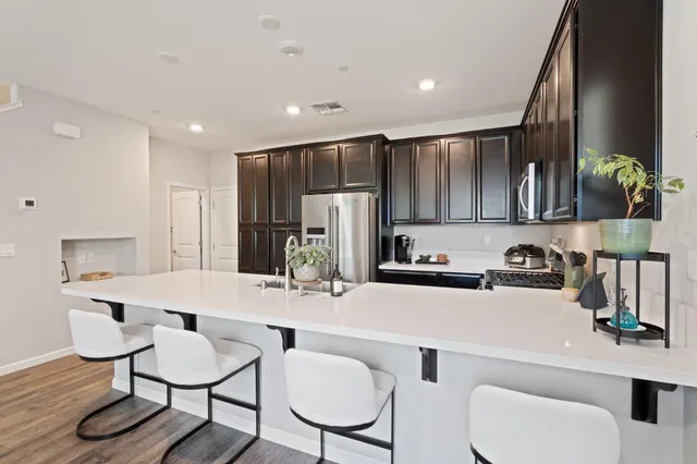 a kitchen with stainless steel appliances a sink a table and chairs in it