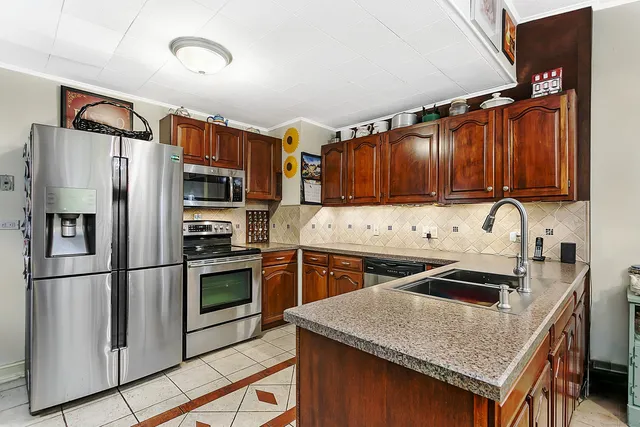 a kitchen with granite countertop stainless steel appliances a stove refrigerator sink and cabinets