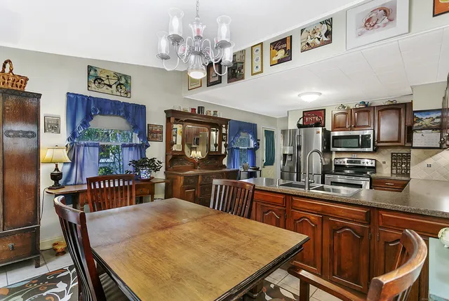 a kitchen with stainless steel appliances granite countertop a sink dishwasher a dining table and chairs with wooden floor