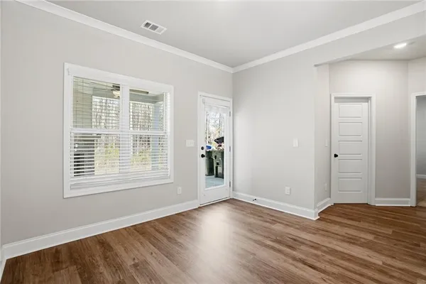 a view of an empty room with wooden floor and a window