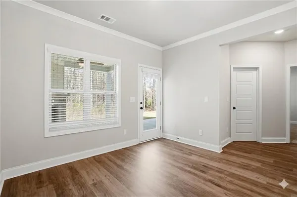 a view of an empty room with wooden floor and a window