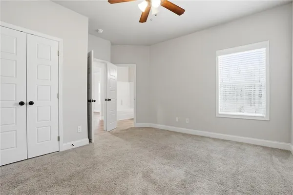 an empty room with chandelier fan and windows
