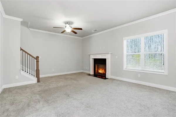 a view of an empty room with chandelier fan and fire place