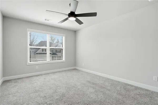 an empty room with a ceiling fan and windows