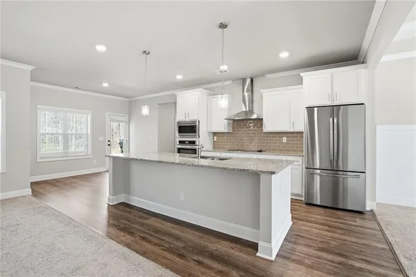 a kitchen with stainless steel appliances granite countertop a refrigerator a sink dishwasher a stove and white countertops with wooden floor